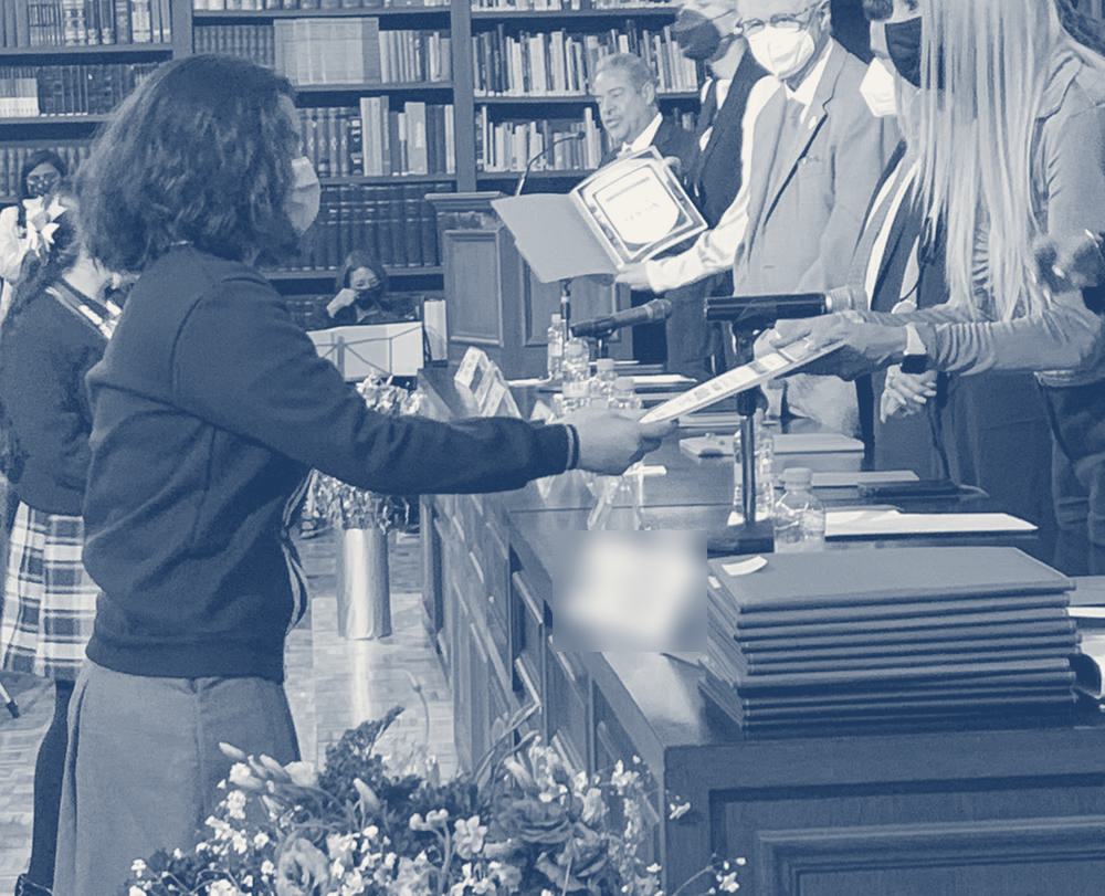 Una estudiante recibe su reconocimiento del presídium en una biblioteca histórica
